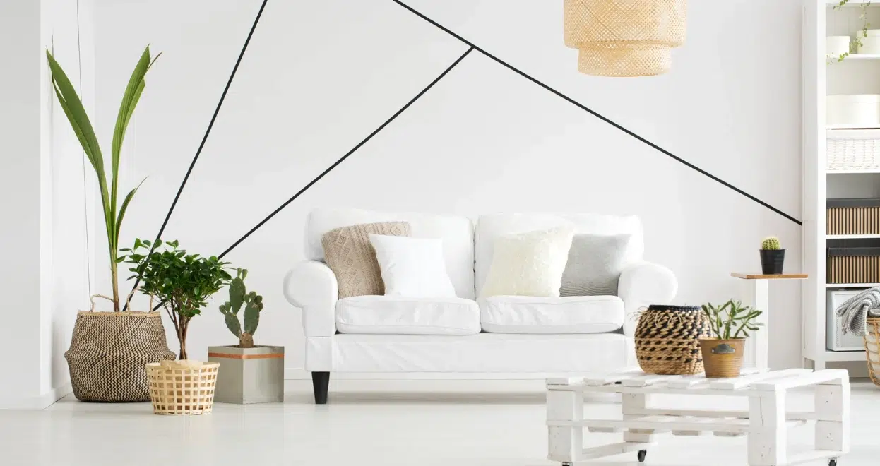 A bright, minimalist living room with a white sofa, several potted plants, and a pallet coffee table, representing a clean and personalized space.